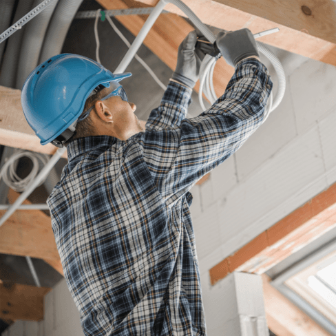 Worker Installing Electrical Wiring in New Building