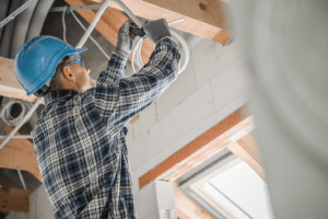Worker Installing Electrical Wiring in New Building