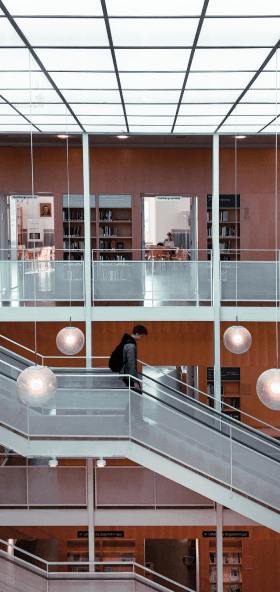 Student Walking Down Modern Library Staircase with Books