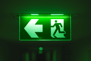 Illuminated Green Emergency Exit Sign in a Dark Room